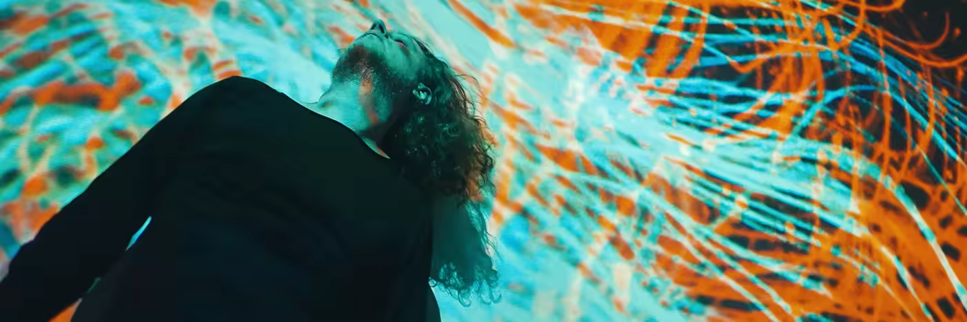 Person with curly hair gazing up at cyan and orange streams.