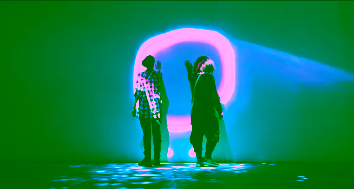Two silhouetted figures near luminous ring with shadows on blue-lit floor.