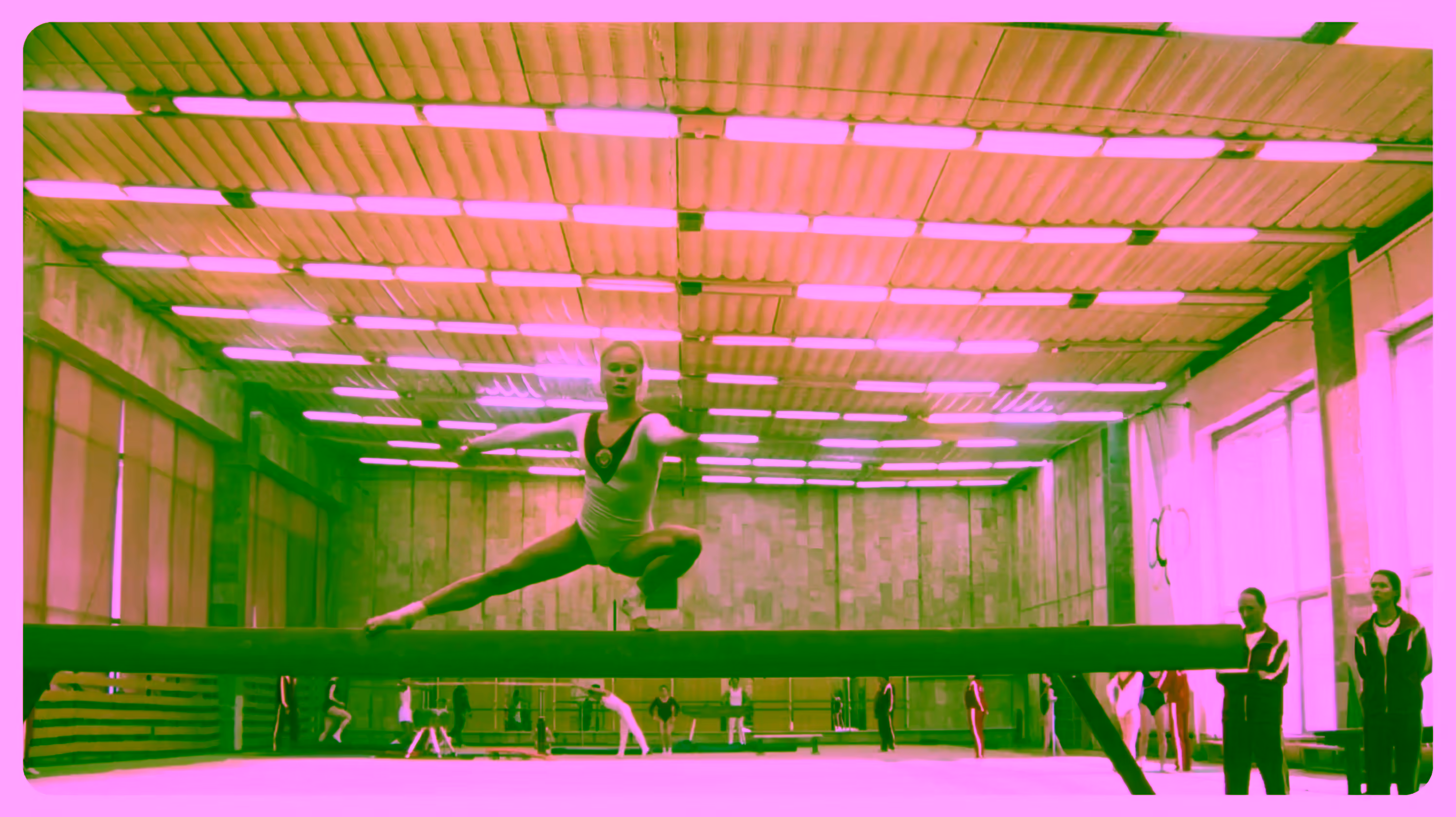 Woman in leotard on balance beam, athletes and coaches in concrete gym hall.
